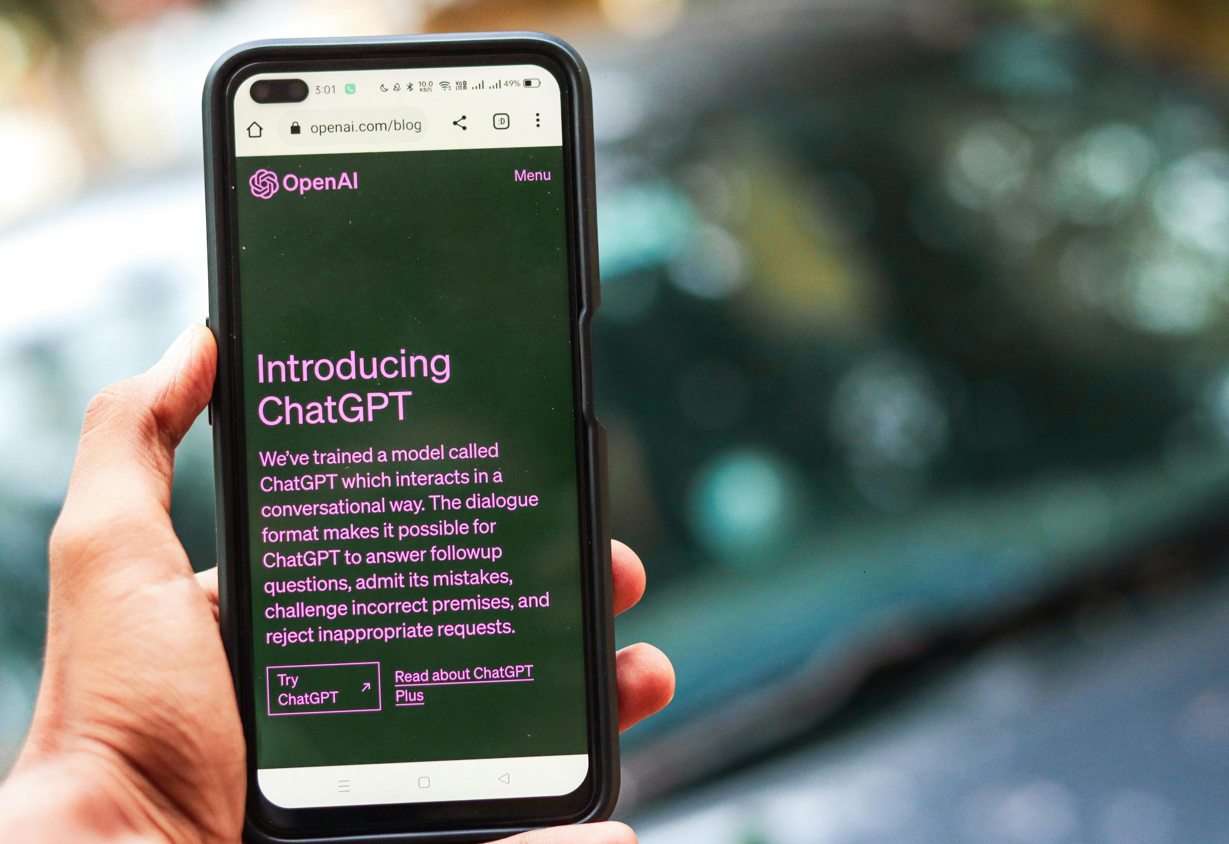 Hand holding a smartphone showing OpenAI’s “Introducing ChatGPT” page, illustrating the rise of generative AI in academic settings.